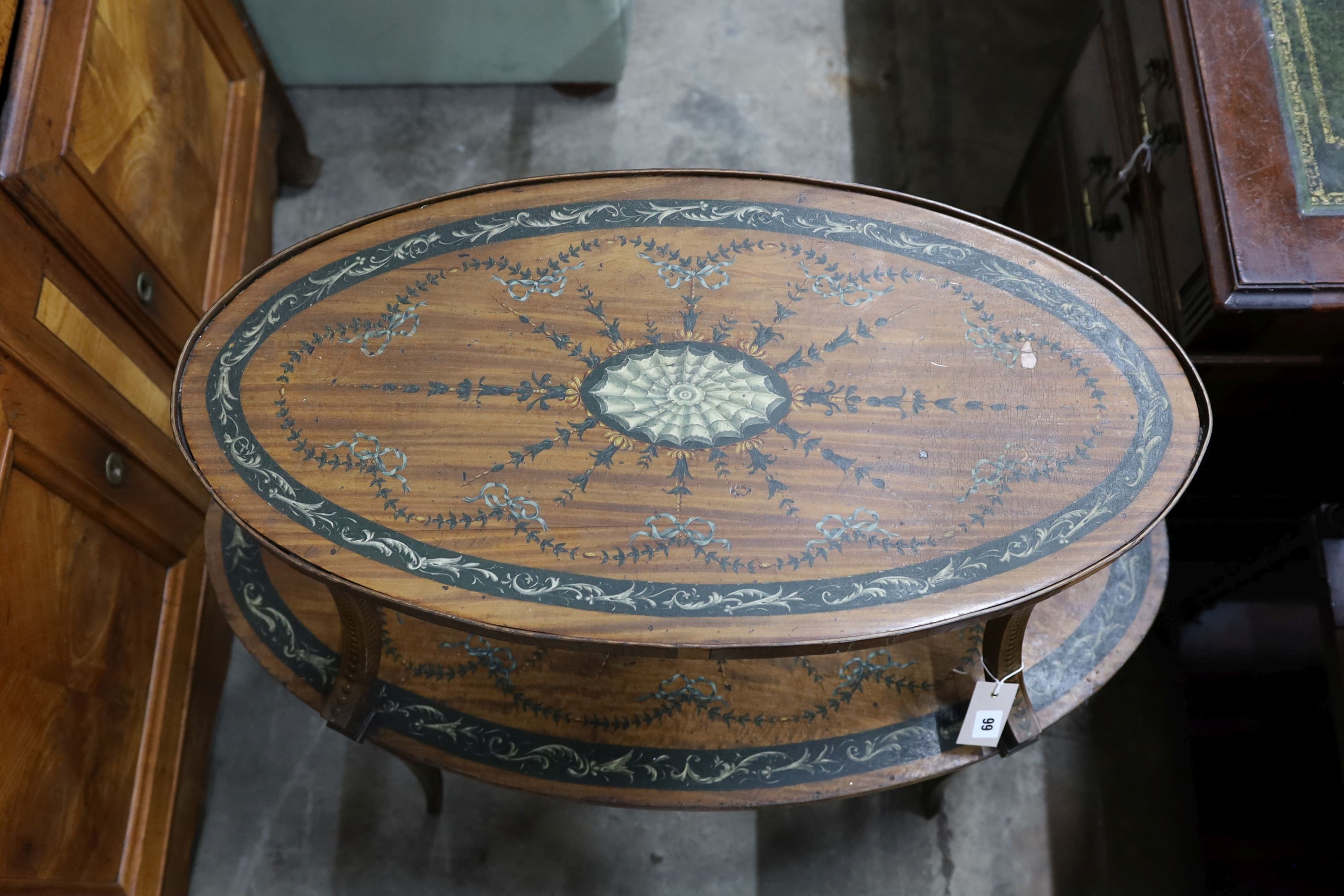 An Edwardian Sheraton revival oval painted satinwood two tier etagere, width 90cm, depth 50cm, height 82cm